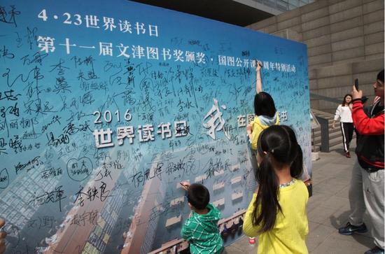读者在活动背景板上签名(国图 张鹏摄)